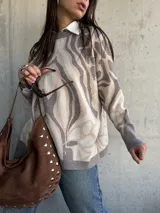 Sweater de punto con diseño abstracto de líneas orgánicas en tonos gris y beige, cuello redondo, manga larga con puños ajustados y corte holgado.