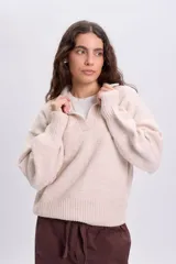 Buzo de punto beige con cuello polo y mangas largas, confeccionado con mezcla de lana y elastano.