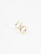 Set de dos anillos dorados, uno con textura facetada y otro con resina transparente.