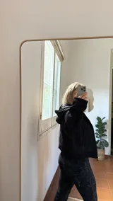 Campera de jogging negra con cierre frontal completo, capucha y bolsillos laterales. Confeccionada en tela frizada en su interior.