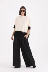 Sweater de punto bicolor con cuello alto, mangas cortas y corte holgado. Presenta un diseño con bloque de color negro en el ruedo y las mangas, y un detalle decorativo de cinto de cuero sintético con hebilla en el frente.