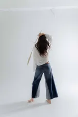 Pantalón jean oxford de tiro medio-alto, ajustado en la cadera con caída amplia y fluida desde la rodilla. Cuenta con cortes verticales y costuras marcadas en las piernas.
