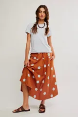 Falda midi de corte A y cintura baja, confeccionada en popelina de algodón color marrón terracota con estampado de lunares celestes.