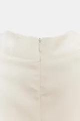 Vestido mini satinado de color blanco, con escote en V pronunciado, mangas cortas casquillo y detalles de botones revestidos en el frente con presillas. Presenta un diseño ajustado en la cintura con costuras estilo corsé y falda corta con vuelo terminada en volante.