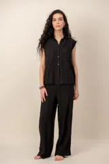 Conjunto compuesto por una blusa sin mangas con cuello camisero, bolsillos frontales y cierre de botones, y un pantalón largo de corte recto y holgado, ambos confeccionados en tejido texturizado de color marrón.
