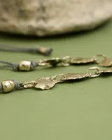 Collar artesanal compuesto por piezas irregulares de alpaca unidas por eslabones, con cordón de algodón natural regulable que permite ajustar el largo.