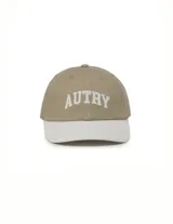 Gorra de béisbol con diseño bicolor, cuerpo en color beige y visera en color blanco. Presenta el logo de la marca bordado en el frente con tipografía universitaria.