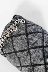 Cartera bandolera de jean negro con diseño acolchado en forma de rombos. Tiene correa de cadena plateada y manija de jean.