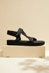 Sandalias planas color blanco, con tiras de tela tipo cinta y cierre ajustable con velcro.