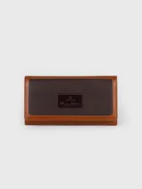 Billetera combinada de cuero en tonos marrón y camel, con solapa frontal de pelo vacuno estampado y detalle de placa con el logo de la marca.