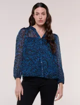 Blusa de silueta holgada y caída fluida, confeccionada en gasa liviana con estampado paisley en tonos azules y negros. Presenta cuello mao con escote en V, cartera frontal con botones, canesú con frunces y mangas largas con puños elastizados.