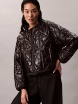 Campera acolchada Calvin Klein de color negro, con diseño matelasseado con monogramas, cuello redondo y cierre frontal de cremallera.
