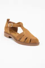 Sandalia tipo cangrejera de gamuza color camel, con diseño de tiras entrelazadas, puntera cerrada y cierre con hebilla metálica lateral.