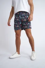 Short de baño con cintura elástica y cordón ajustable, confeccionado en tela ligera de secado rápido. Presenta un estampado botánico integral en tonos amarillos, blancos y azules, con dos bolsillos delanteros y uno posterior.