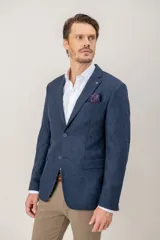 Saco de vestir con diseño de espiga en color marrón, confeccionado en mezcla de lana y seda. Presenta solapas clásicas, cierre frontal de dos botones y bolsillos laterales con solapa.