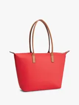 Cartera tote Tommy Hilfiger de nailon rojo, con cierre de cremallera, asas superiores de cuero sintético tostado y monograma metálico TH en la parte delantera.