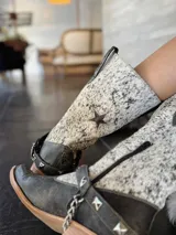 Botas de caña media de cuero negro con puntera cuadrada, detalle de cuero con estampado animal en la caña y correa con tachas alrededor del tobillo.