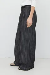 Pantalón de jean azul oscuro de tiro alto, con diseño holgado de pierna ancha, pinzas en la cintura y costuras a la vista.