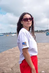 Remera blanca de algodón, de corte holgado y manga corta, con un parche rectangular bordado en la manga derecha que presenta un diseño gráfico colorido.