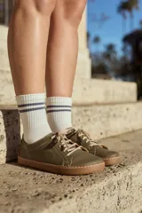 Championes de cuero natural color verde oliva, con cordones beige y suela de goma marrón. Diseñados bajo los principios del barefoot, con puntera amplia y suela fina y flexible.