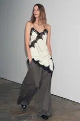 Vestido corto de satén color azul marino oscuro, con escote en V y tirantes finos. Presenta aplicación de encaje en el escote y el bajo es asimétrico con terminación de encaje.