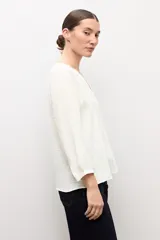 Blusa negra de manga larga con diseño de tejido plumeti y escote en V.
