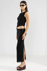 Falda midi negra de punto con abertura lateral y detalle de botón metálico con logo.