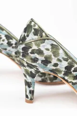 Zapatos de tacón estilo salón con diseño clásico, confeccionados en arpillera con estampado animal print en tonos verdes. Presentan ribetes de piel tornasolada que dividen las piezas de la puntera, laterales y talonera, con interior en piel y suela de cuero.