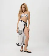 Pareo de playa rectangular confeccionado en viscosa liviana de color blanco, con estampado de caracolas marinas y detalles gráficos en negro en los bordes.