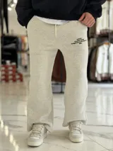 Pantalón jogging oversize color gris melange, con cordón ajustable en la cintura, bolsillos laterales y estampa con texto en la pierna izquierda.
