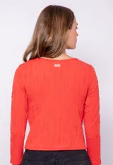 Top rojo de manga larga y cuello redondo con textura sutil en relieve, corte ajustado.