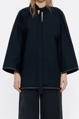 Camisa larga azul marino de algodón, con cuello mao con lazo a modo de cierre y manga larga ancha con pespunte bordado en puños y bajo.