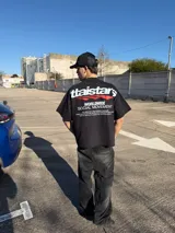Remera oversize negra con diseño gráfico estampado en el pecho y en la espalda con inscripciones y líneas rojas.