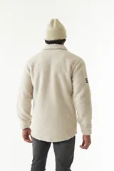 Sobrecamisa de sherpa color crema con cuello camisero, cierre frontal con botones a presión y bolsillo de parche en el pecho. El modelo usa talle M.