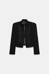 Blazer negro de corte entallado con cuello mao y hombreras marcadas. Presenta un diseño de inspiración militar con detalles de bordados tipo pasamanería a tono y botones dorados en la parte delantera. Cuenta con cierre frontal con gancho metálico y mangas largas.