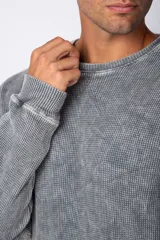 Buzo de corte oversize confeccionado en tela waffle de algodón con proceso de teñido acid wash. Presenta cuello redondo con detalle de costura en X y mangas largas con puños acanalados.