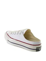 Zapatillas tipo mule Converse Chuck 70, confeccionadas en lona de algodón color blanco. Presentan el diseño clásico de la puntera de goma, cordones al tono y suela de goma con la característica franja roja y azul.