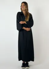 Vestido largo de seda y viscosa color negro, con cuello tipo camisa, escote en V y mangas largas con terminación abullonada.