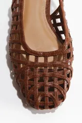 Zapatos destalonados color marrón con diseño trenzado, punta redondeada y pulsera ajustable con hebilla metálica.
