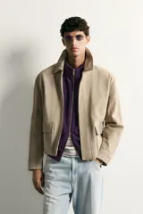 Cazadora relaxed fit de piel y ante color beige, con cuello solapa, manga larga con puño, bolsillos delanteros con solapa y cierre frontal oculto con cremallera y botones a presión.