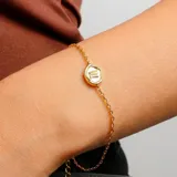 Pulsera dorada con cadena fina y dije ovalado con el signo zodiacal Escorpio.