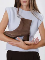 Bota corta de cuero color marrón, con plataforma forrada y taco cuadrado de madera oscura. Presenta un diseño minimalista de caña media con cierre lateral interno.