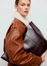 Bolso tipo tote color marrón oscuro, confeccionado en poliuretano con diseño estructurado y amplio espacio principal.