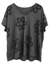 Remera negra de manga corta con escote en V y diseño amplio, decorada con grandes aplicaciones florales en relieve de textura rústica.
