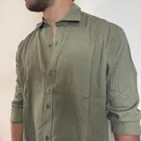 Camisa de manga larga confeccionada en lino, color blanco, con cuello clásico y cierre frontal de botones.