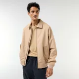 Campera de twill beige con cierre frontal, cuello camisero, bolsillos laterales con solapa y puños y cintura elastizados de rib.