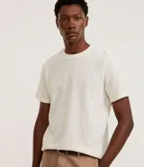 Remera de hombre color crudo, de punto calado con textura de encaje, cuello redondo y mangas cortas. Corte regular. Confeccionada en poliéster y algodón.