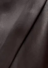 Falda pantalón corta de efecto piel en color bordó, de tiro medio y diseño cruzado con cierre de cremallera lateral.
