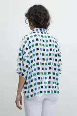 Blusa oversized con estampa geométrica de cuadrados azules y verdes sobre fondo blanco.