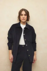 Sobrecamisa de pana color beige, con cuello camisero, cierre frontal con botones metálicos, mangas largas con puños abotonados y lazo ajustable en la cintura.